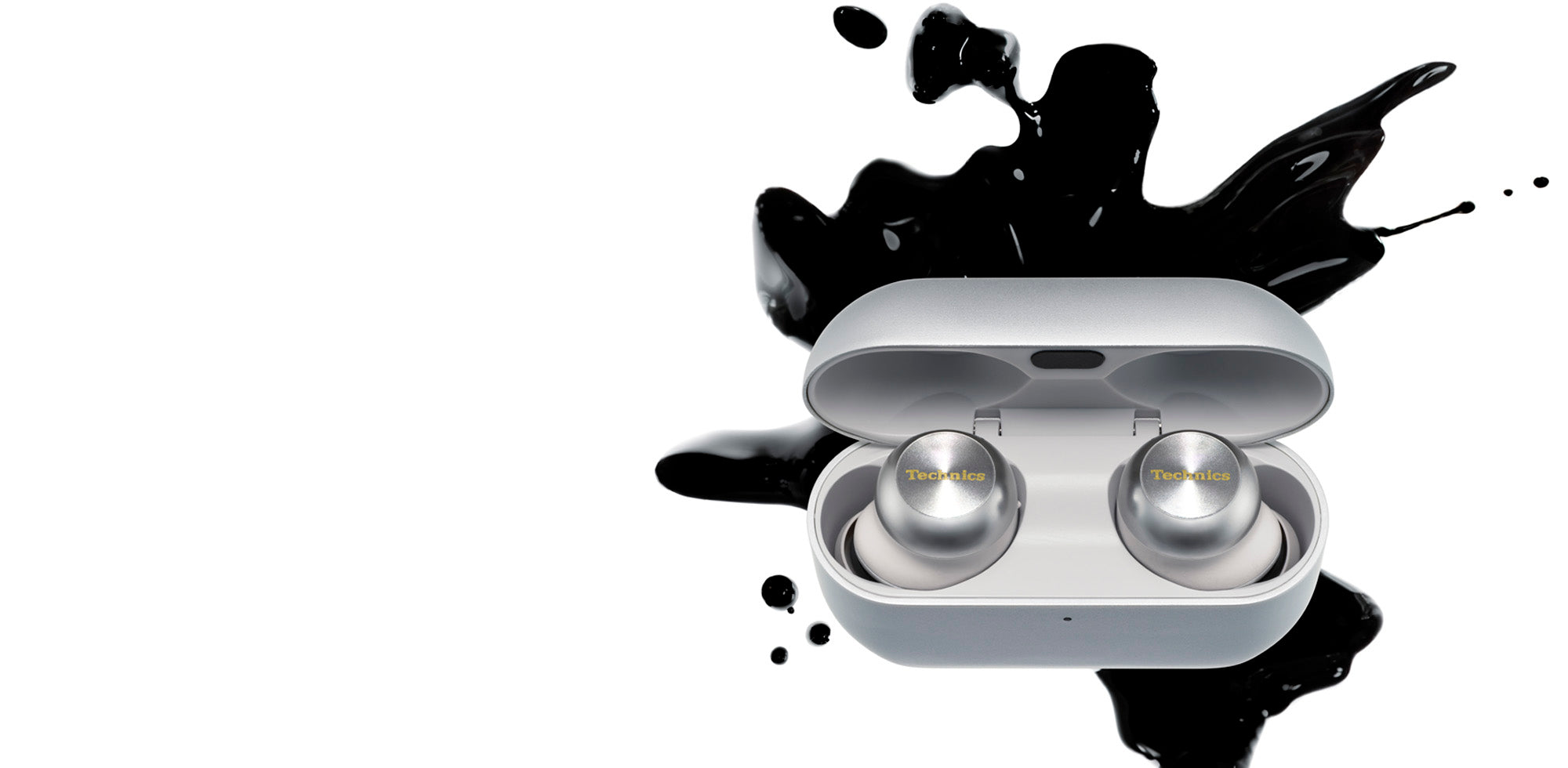 Technics silver AZ100 earbud headphones in charging case with black ink splatter in the background